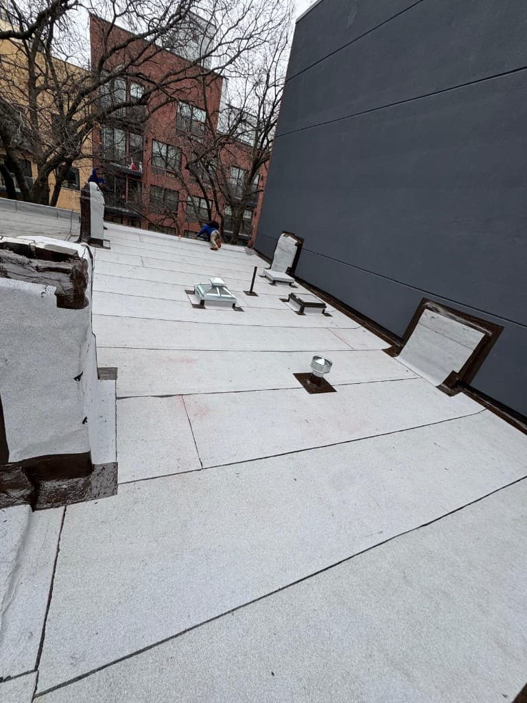 Flat roof with a new granulated cap sheet, flashed skylights, a vent pipe and flashed wall junctions