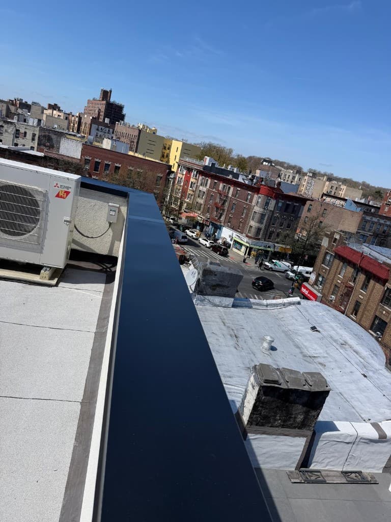Dark sheet-metal parapet coping seen from the corner of the roof, with the street below
