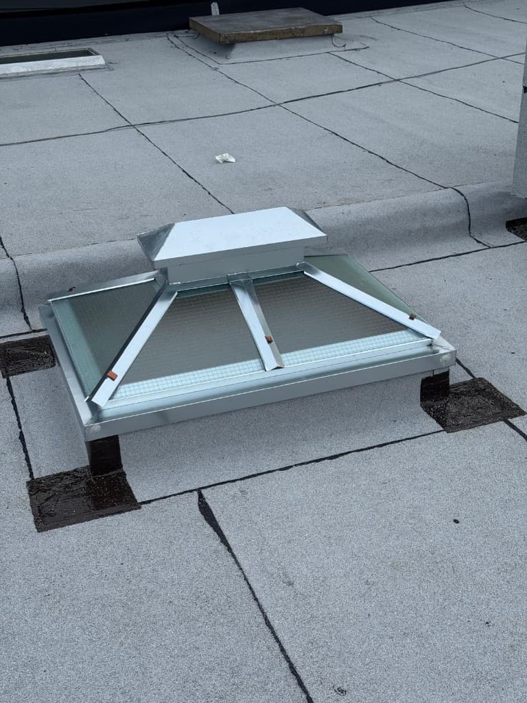 Pyramid skylight with wired glass, a new galvanized metal frame and cap, set on a flashed curb on a flat roof