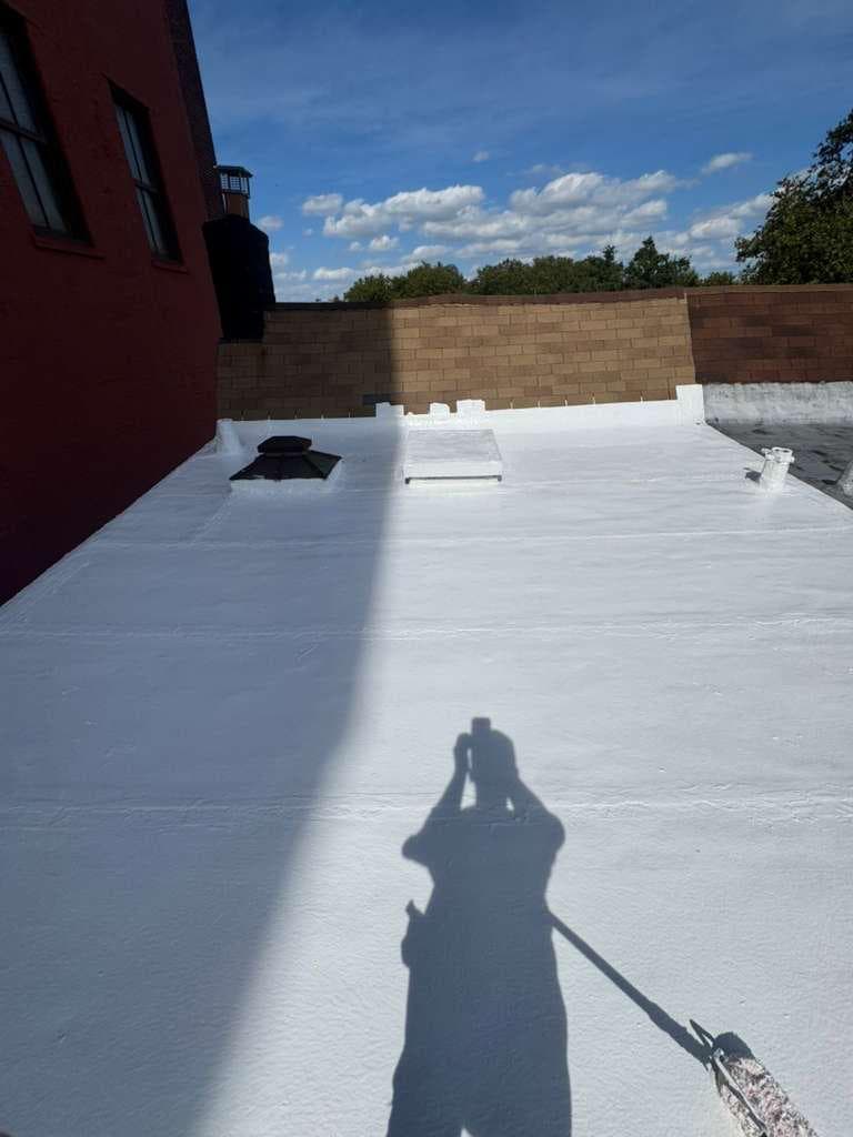 Finished white roof coating running up to the parapet wall and around a skylight